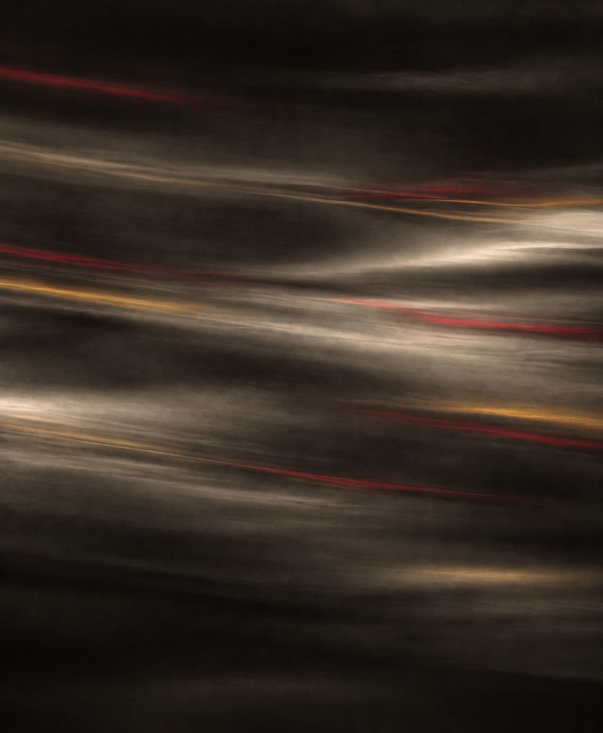 Dark, flowing streaks of warm light in red and gold